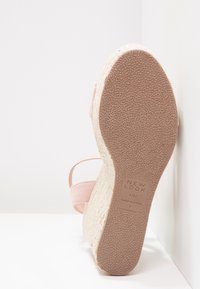 Semelle d'une sandale compensée rose avec semelle en caoutchouc texturée, plateforme en jute tissée et étiquette de taille indiquant "NEW LOOK 4/37 MADE IN CHINA L."