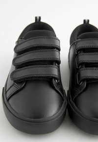 Zwarte leren schoenen met drie klittenbandsluitingen, ronde neuzen, rubberen zolen en een gladde afwerking. Inclusief een trekband aan de hiel.