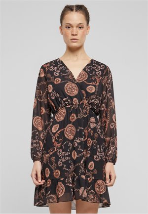 Mustat läpinäkyvät mekko pitkillä hihoilla, V-pääntiellä ja joustavalla vyötäröllä. Siinä on pronssiketju ja kukkakuvioita, viimeistelty röyhelöhelmalla.