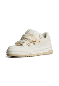 Witte sportieve schoenen met een geperforeerde mesh bovenzijde, contrasterende gevoerde tong en dikke rubberen zool met een subtiel patroon en ronde vorm.
