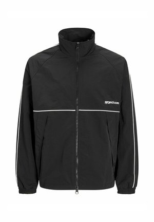 Schwarze Jacke mit Reißverschluss und hohem Kragen, weißen Paspeln über Brust und Ärmeln, elastischen Bündchen und kleinem weißen "project core"-Logo auf der linken Brust.