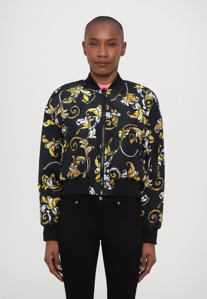 Black bomber jacket with intricate gold and white floral patterns, ribbed cuffs and hem, front zipper, and a contrasting pink collar.