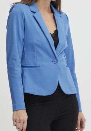 Blazer bleu en tissu lisse, doté d'un col à revers, d'une fermeture à un bouton et de poches avant. Assorti à un top et un pantalon noirs.