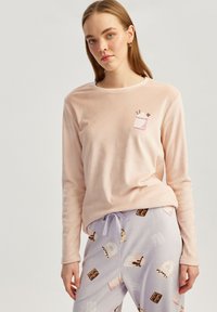 Top rose à manches longues avec un graphique de tasse ; associé à un pantalon violet clair comportant un imprimé de desserts, comprenant des gâteaux et des formes de chocolat.