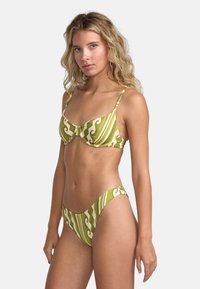 Green bikini set featuring a patterned top with a bow detail and matching low-rise bottom, made from smooth, stretch fabric.
