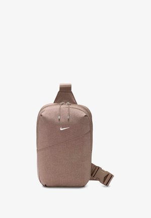 Mała brązowa torebka na ramię z regulowanym paskiem i podwójnym zamkiem błyskawicznym, z białym logo Nike w kształcie łyżwy z przodu.