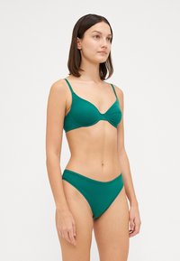 Πράσινο μπικίνι σετ που διαθέτει μαξιλαρωμένο bralette με ρυθμιζόμενους ιμάντες και ψηλόμεσο κάτω μέρος. Λείο ύφασμα με ελάχιστες ραφές.