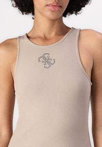 Beige geribbelde tanktop met een ronde hals en een decoratieve logo geborduurd met donkere draad op de borst.
