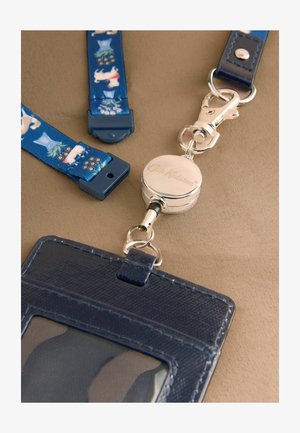 Sinine nahast kaarditasku läbipaistva aknaga, mis on kinnitatud kokkutõmmatava hõbedase rinnamärgiklambriga ja sinise nööriga, millel on koera ja lille mustrid.