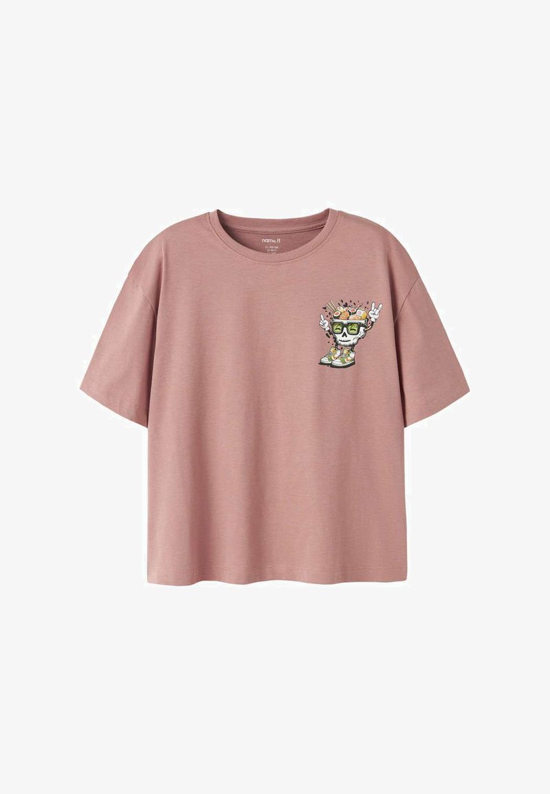 T-shirt rose poussiéreux à manches courtes avec un petit motif de crâne portant des lunettes de soleil, des baskets, et faisant des signes de la main rock clignotants sur le côté gauche de la poitrine.