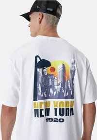 T-shirt bianco con una grafica che presenta uno skyline cittadino, un pallone da basket e la scritta "NEW YORK 1920" in colori vivaci. Collo rotondo e vestibilità comoda.
