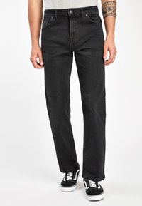 Jeans din denim negru cu un croi drept, având buzunare frontale, un buton metalic și cusături albe. Asortați cu adidași negri și albi.