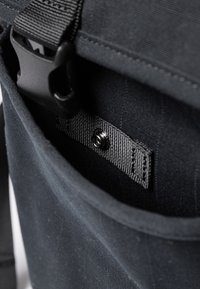 Borsa nera in tessuto con una tasca interna foderata texture, dotata di una tracolla con una fibbia in plastica nera e una chiusura a scatto sicura per l'organizzazione.