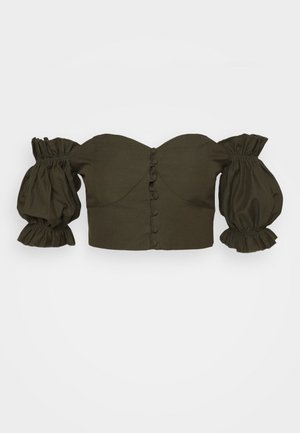 Donkergroene off-shoulder cropped top met opgeblazen lange mouwen en met stof overtrokken knopen aan de voorkant in het midden.