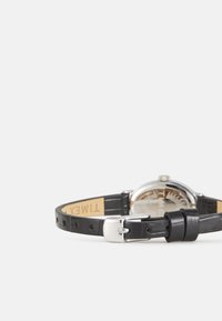 Montre à bracelet en cuir noir avec un boîtier rond en argent, un verre clair et un design de cadran minimaliste. Comprend une boucle argentée et un dessous en tan.