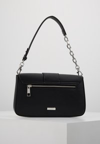 Black rectangular handbag with silver zipper pocket and chain-link strap, displayed on white pedestal against light background.