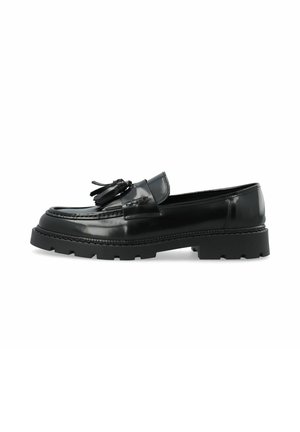 Mocassin en cuir noir avec semelle épaisse à crampons et décoration à pompons sur le dessus, présenté en profil latéral sur fond blanc.
