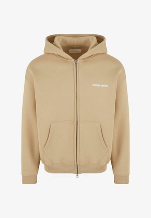 Beige huppari vetoketjulla, valmistettu puuvillasekoitteesta. Varustettu kengurupussilla, ribbaussein ja helman lisäksi rinnassa "ANOTHER COTTON" -logo.