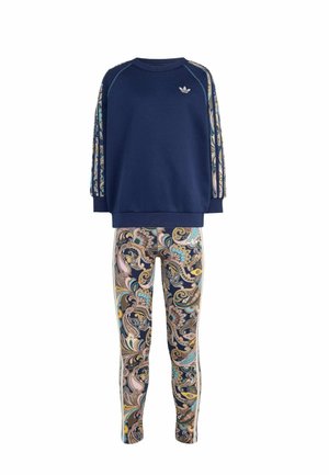 Granatowa bluzka z długim rękawem z wzorzystymi paskami paisley na rękawach i wielokolorowymi legginsami w wzór paisley.