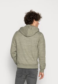 Grijze hoodie met een gestructureerde, gemêleerde afwerking, voorzien van een trekkoordkap en ribgebreide manchetten en zoom. De achterkant toont een eenvoudig ontwerp.