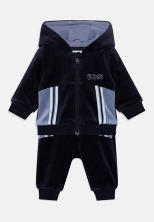 Marineblauwe en lichtblauwe baby trainingspak met capuchon, rits aan de voorkant, ribgebreide manchetten, gestreepte zijpanelen en 'BOSS' logo op de borst.