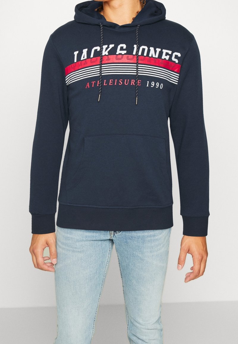 Sudadera azul marino con bolsillo canguro, capucha con cordón y franjas en rojo y blanco que presentan el texto "JACK & JONES".