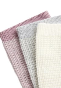 Tri zložené pletené vlnené šály v pastelovej ružovej, šedej a krémovej farbe, usporiadané prekrytím na bielom pozadí.