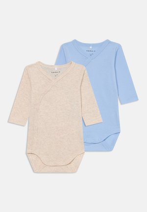 Två långärmade bodysuits: en beige, en ljusblå. Båda har en omslagsdesign med tryckknappar och är gjorda av mjuk bomull.