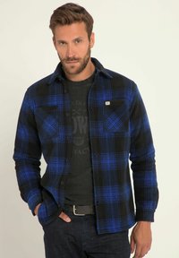 Zwart en blauw geruit flanellen overhemd met een knoopsluiting, voorzien van een borstzak en een zachte textuur, gedragen over een zwart T-shirt.