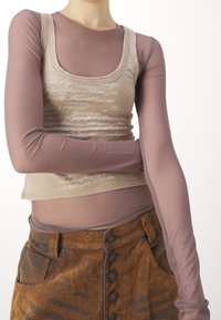 Beige linne med vit text, lager på ett mauve långärmad åtsittande topp. Brun knäppt kjol med textur och sidoficka detaljer.