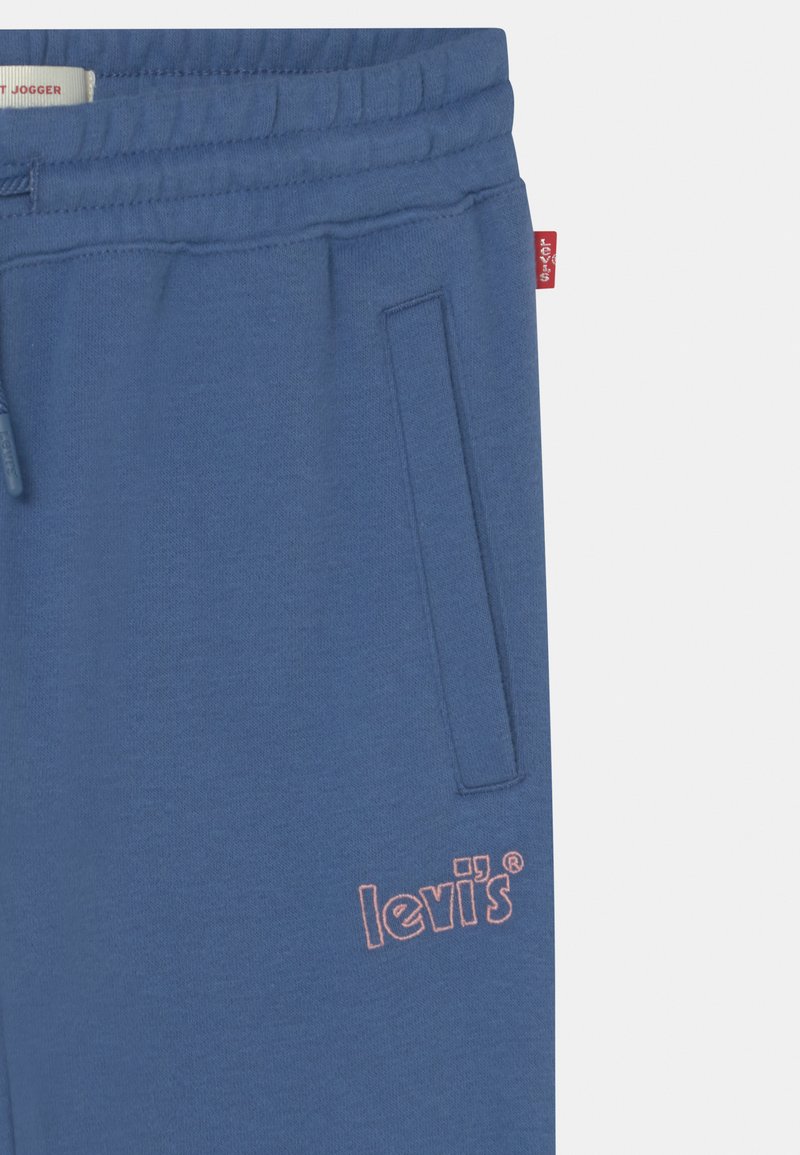 Pantalons de jogging bleus en tissu doux avec une taille à cordon de serrage, dotés de poches latérales et d'un logo "Levi's" brodé en rose.