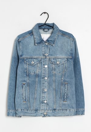 Light blue denim jacket with button front, two chest flap pockets with buttons, and side slit pockets hanging on black hanger.