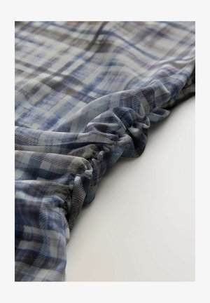 Niebieska i szara tkanina w kratę o miękkim, teksturowanym wykończeniu, z marszczonym wykończeniem na krawędzi. Tkanina delikatnie opada.