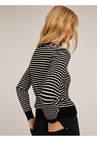 Czarny i biały sweter w paski z ryflowaną teksturą, dopasowany krój oraz czarne mankiety i dół, widok z tyłu.