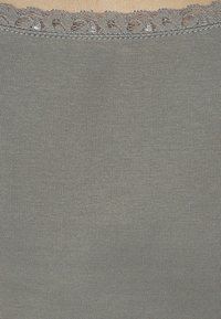 Šedá žebrovaná tkanina s jemným krajkovým lemem na horním okraji, která ukazuje hladkou texturu a decentní lesk. Žádné vzory ani další detaily.