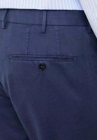 Marineblaue Hose mit glattem Textur, einer Gesäßtasche und einem schwarzen Knopf, entworfen mit Gürtelschlaufen.