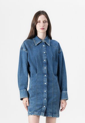 Denim shirt dress in medium blue with long sleeves, a pointed collar, front button closure, and side pockets; features visible stitching.