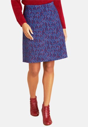 Blaue gemusterte A-Linien-Rock mit floralen Designs in Rot und Weiß, aus strukturiertem Stoff. Kombiniert mit roten Schnür-Stiefeletten.