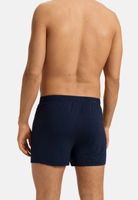 Boxer shorts blu navy realizzati in morbido cotone, con vita elastica e un colore uniforme senza pattern o grafiche visibili.