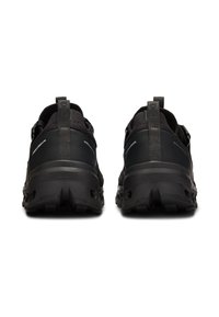 Baskets de sport noires avec une tige en maille texturée, un talon renforcé et une semelle en caoutchouc épaisse présentant un motif de bande de roulement profond. Accents réfléchissants.