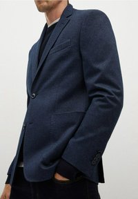 Granatowa, dopasowana marynarka z teksturowanej tkaniny, z pojedynczym guzikiem, klapami z wycięciem i bocznymi kieszeniami. Mankiety zdobione guzikami.