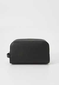 Trousse de toilette en cuir noir de forme rectangulaire, surface texturée, fermeture zippée sur le dessus et poignée latérale pour un transport facile.