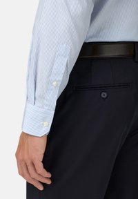 Světle modrá a bílá pruhovaná košile s knoflíkovým manžetovým zapínáním, spárovaná s tmavými kalhotami. Nabízí hladký materiál a přizpůsobený střih.