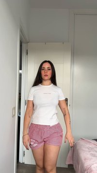 T-shirt blanche à manches courtes avec le logo "BENETTON", accompagnée d'un short à rayures rouges et blanches. Tissu lisse avec une taille élastique.