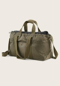 Bolsa de deporte de nailon verde con asas dobles y una correa de hombro desmontable. Cuenta con una parte superior con cremallera y un detalle de logo en el frente. Textura suave.