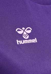 Białe stylizowane logo pszczoły i tekst „hummel” na fioletowym, teksturowanym materiale.