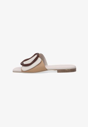 Flad sandalsandal med beige og hvide læderstropper og en stor mørkebrun rund spænde, lav træhæl, åben tå-design.