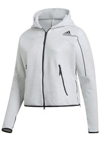 Veste à capuche zippée Adidas gris clair avec fermeture éclair noire, poches latérales zippées et bordures noires aux manches et à l’ourlet.