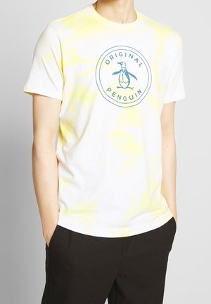 Camiseta blanca de manga corta con un patrón de tie-dye amarillo, que presenta un logotipo circular con un gráfico de un pingüino en azul en el centro.