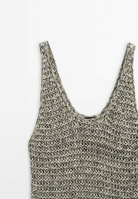 Haut sans manches tissé à la main avec une encolure dégagée en fil beige et noir formant un motif texturé en maille ajourée.